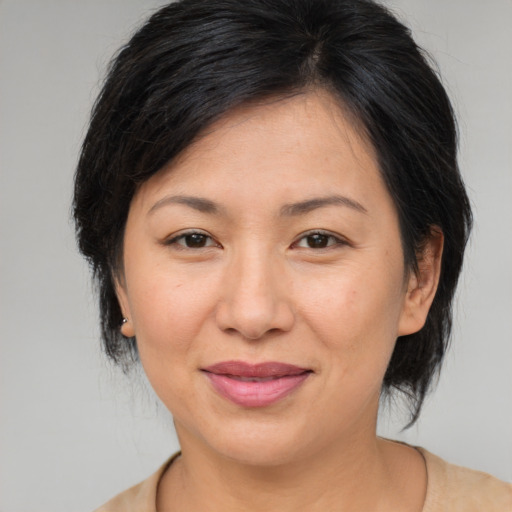 Joyful asian adult female with medium  brown hair and brown eyes