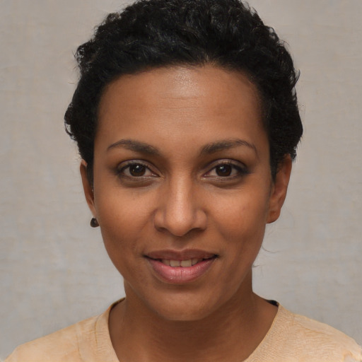 Joyful black young-adult female with short  black hair and brown eyes