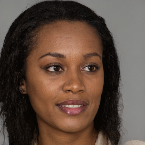 Joyful black young-adult female with long  brown hair and brown eyes