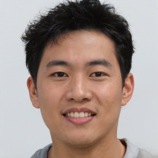 Joyful asian young-adult male with short  brown hair and brown eyes