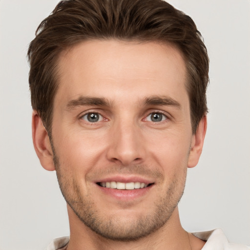 Joyful white young-adult male with short  brown hair and grey eyes