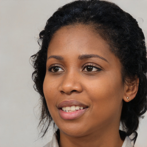 Joyful black young-adult female with long  black hair and brown eyes