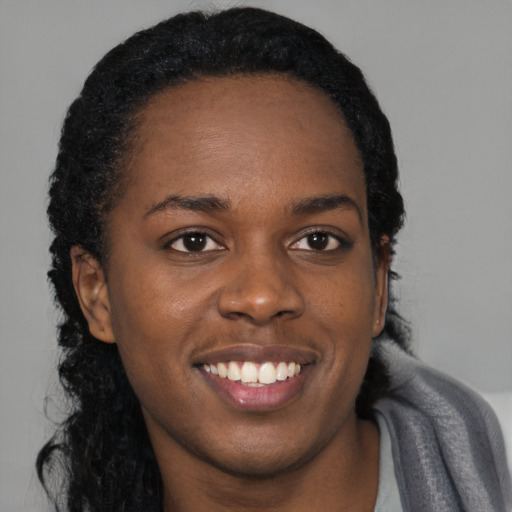 Joyful black young-adult female with long  black hair and brown eyes