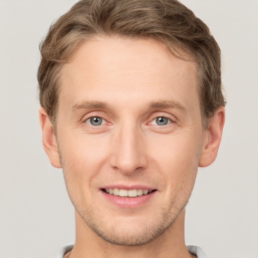 Joyful white young-adult male with short  brown hair and grey eyes