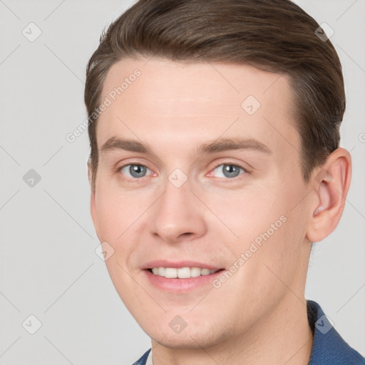 Joyful white young-adult male with short  brown hair and grey eyes