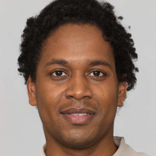 Joyful black young-adult male with short  brown hair and brown eyes