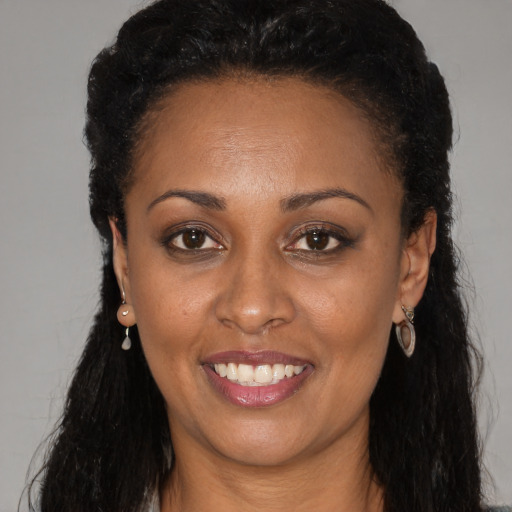 Joyful black adult female with long  black hair and brown eyes