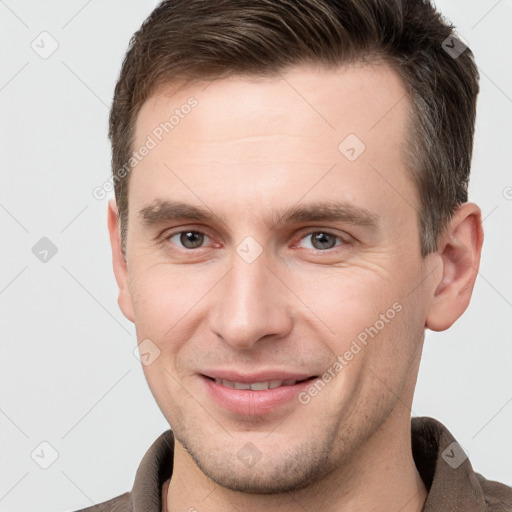 Joyful white young-adult male with short  brown hair and grey eyes