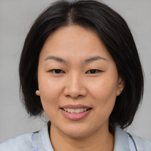 Joyful asian adult female with medium  brown hair and brown eyes