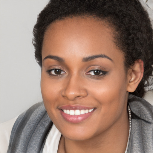 Joyful black young-adult female with long  brown hair and brown eyes