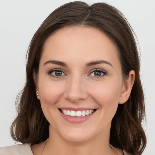 Joyful white young-adult female with medium  brown hair and grey eyes