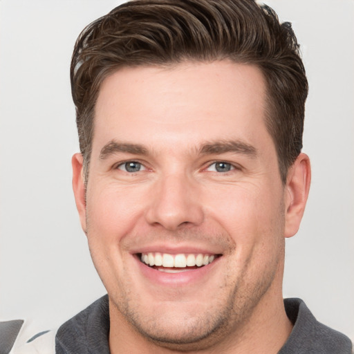 Joyful white young-adult male with short  brown hair and grey eyes