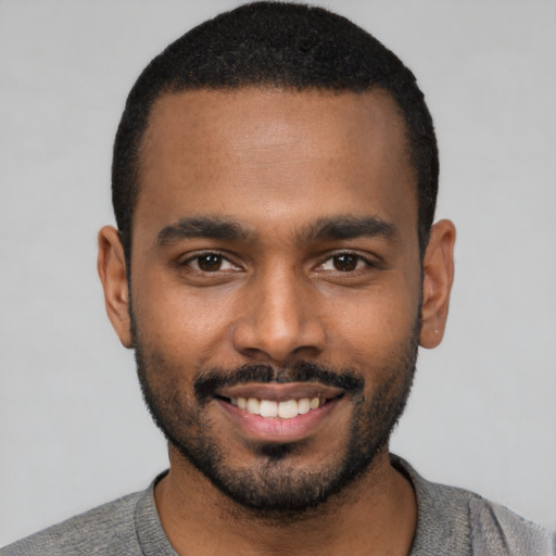 Joyful black young-adult male with short  black hair and brown eyes