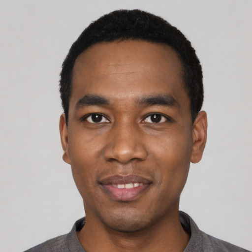 Joyful black young-adult male with short  black hair and brown eyes