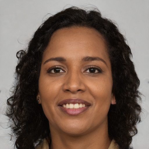 Joyful black young-adult female with long  brown hair and brown eyes