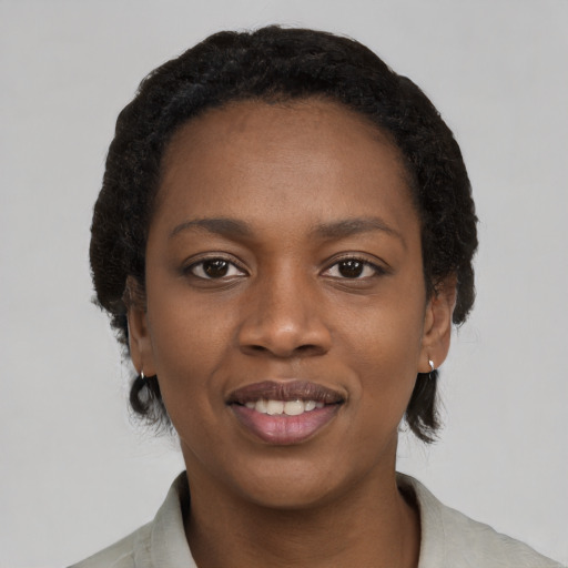 Joyful black young-adult female with short  black hair and brown eyes