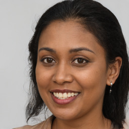 Joyful black young-adult female with long  brown hair and brown eyes