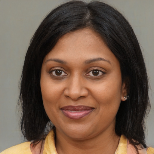 Joyful black adult female with long  brown hair and brown eyes