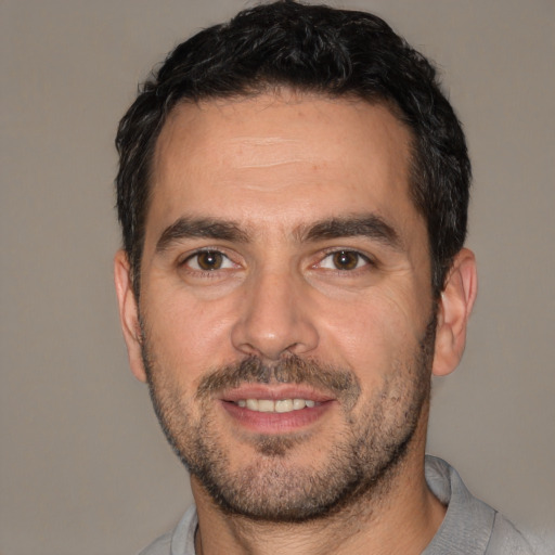 Joyful white adult male with short  black hair and brown eyes