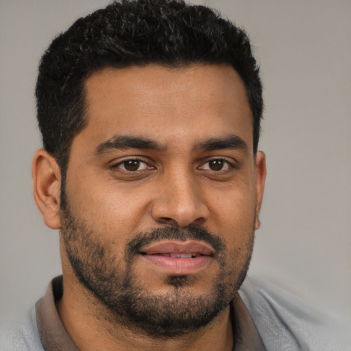 Joyful latino young-adult male with short  black hair and brown eyes