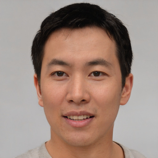 Joyful asian young-adult male with short  brown hair and brown eyes