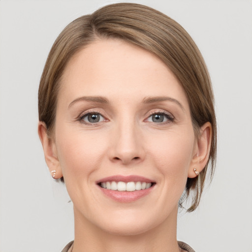 Joyful white young-adult female with medium  brown hair and grey eyes