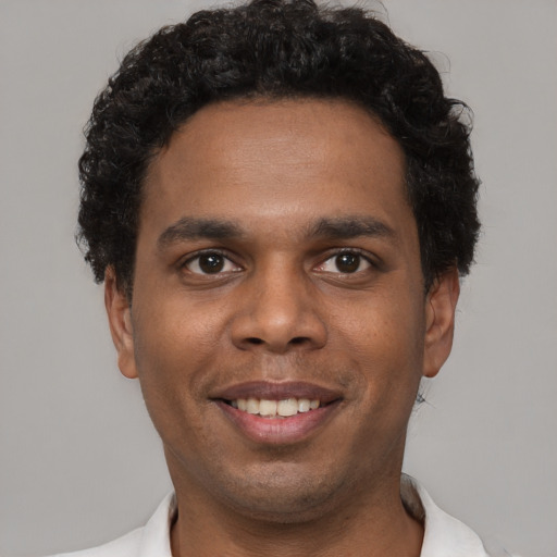 Joyful black young-adult male with short  black hair and brown eyes