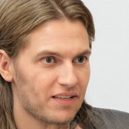 Joyful white young-adult male with long  brown hair and grey eyes