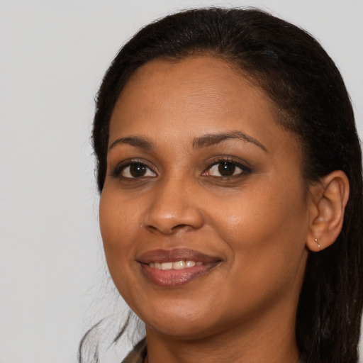 Joyful black young-adult female with long  brown hair and brown eyes