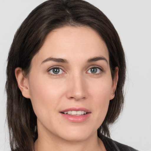 Joyful white young-adult female with medium  brown hair and grey eyes