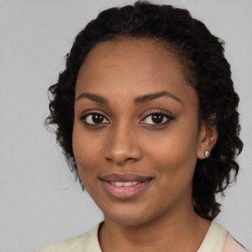 Joyful black young-adult female with long  black hair and brown eyes