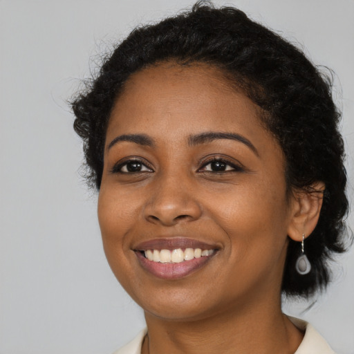 Joyful black young-adult female with medium  black hair and brown eyes