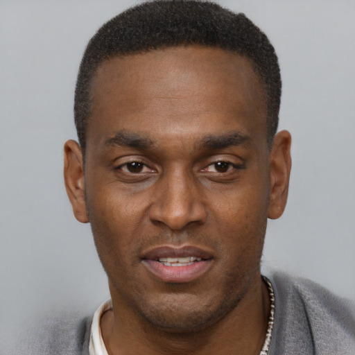 Joyful black young-adult male with short  brown hair and brown eyes