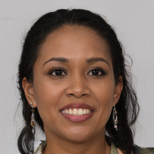 Joyful black young-adult female with long  brown hair and brown eyes