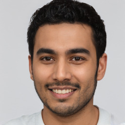 Joyful latino young-adult male with short  black hair and brown eyes