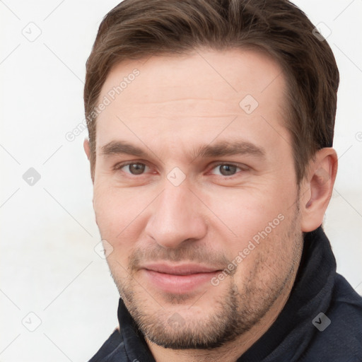 Joyful white young-adult male with short  brown hair and grey eyes