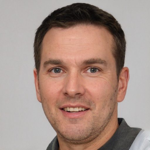 Joyful white adult male with short  brown hair and grey eyes