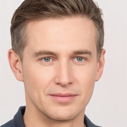 Joyful white young-adult male with short  brown hair and grey eyes