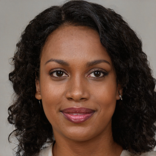 Joyful black young-adult female with long  brown hair and brown eyes