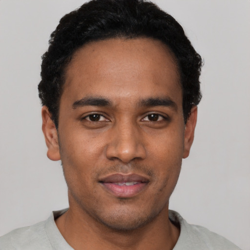 Joyful black young-adult male with short  black hair and brown eyes