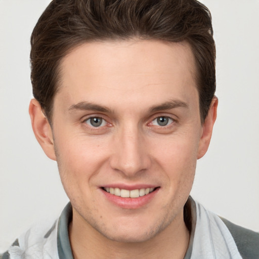 Joyful white young-adult male with short  brown hair and grey eyes