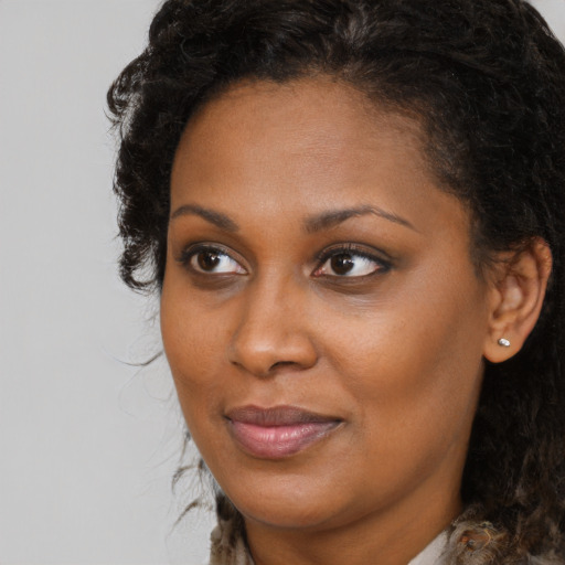 Joyful black young-adult female with long  brown hair and brown eyes