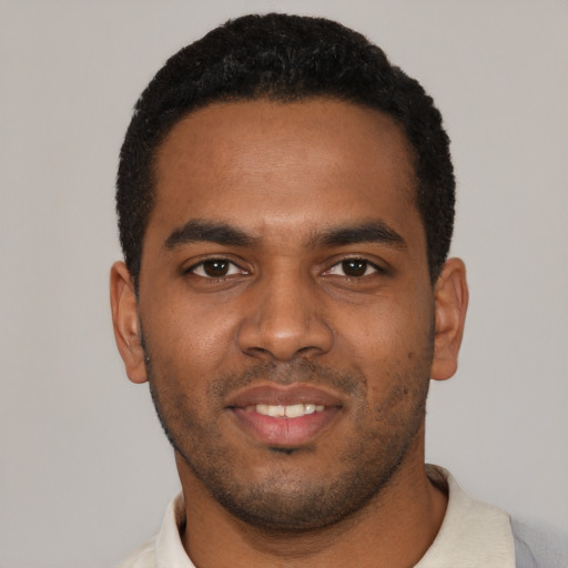 Joyful black young-adult male with short  black hair and brown eyes