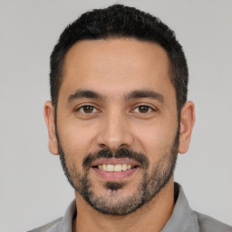 Joyful latino young-adult male with short  black hair and brown eyes