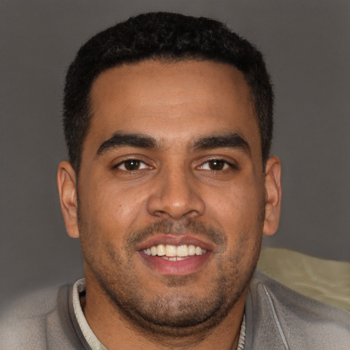 Joyful black young-adult male with short  black hair and brown eyes