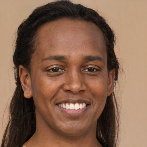Joyful black adult female with long  brown hair and brown eyes