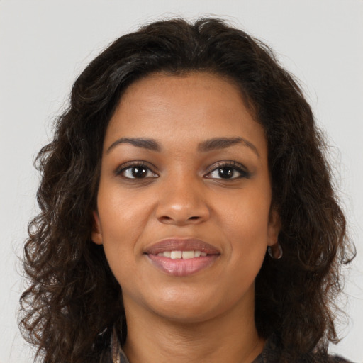 Joyful black young-adult female with long  brown hair and brown eyes