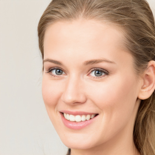 Joyful white young-adult female with long  brown hair and blue eyes