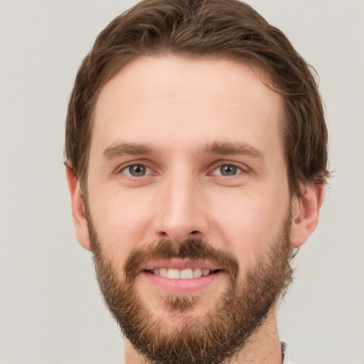 Joyful white young-adult male with short  brown hair and grey eyes