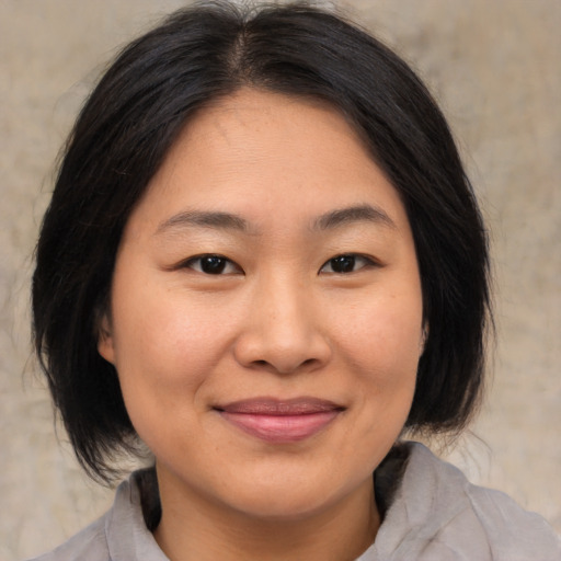 Joyful asian adult female with medium  brown hair and brown eyes